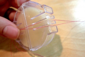 Threads being pulled through beeswax holder.