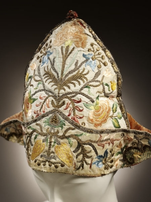 A mid-18th century undress cap from Italy. It is decorated with stylised flowers, as well as metal threads and spangles.