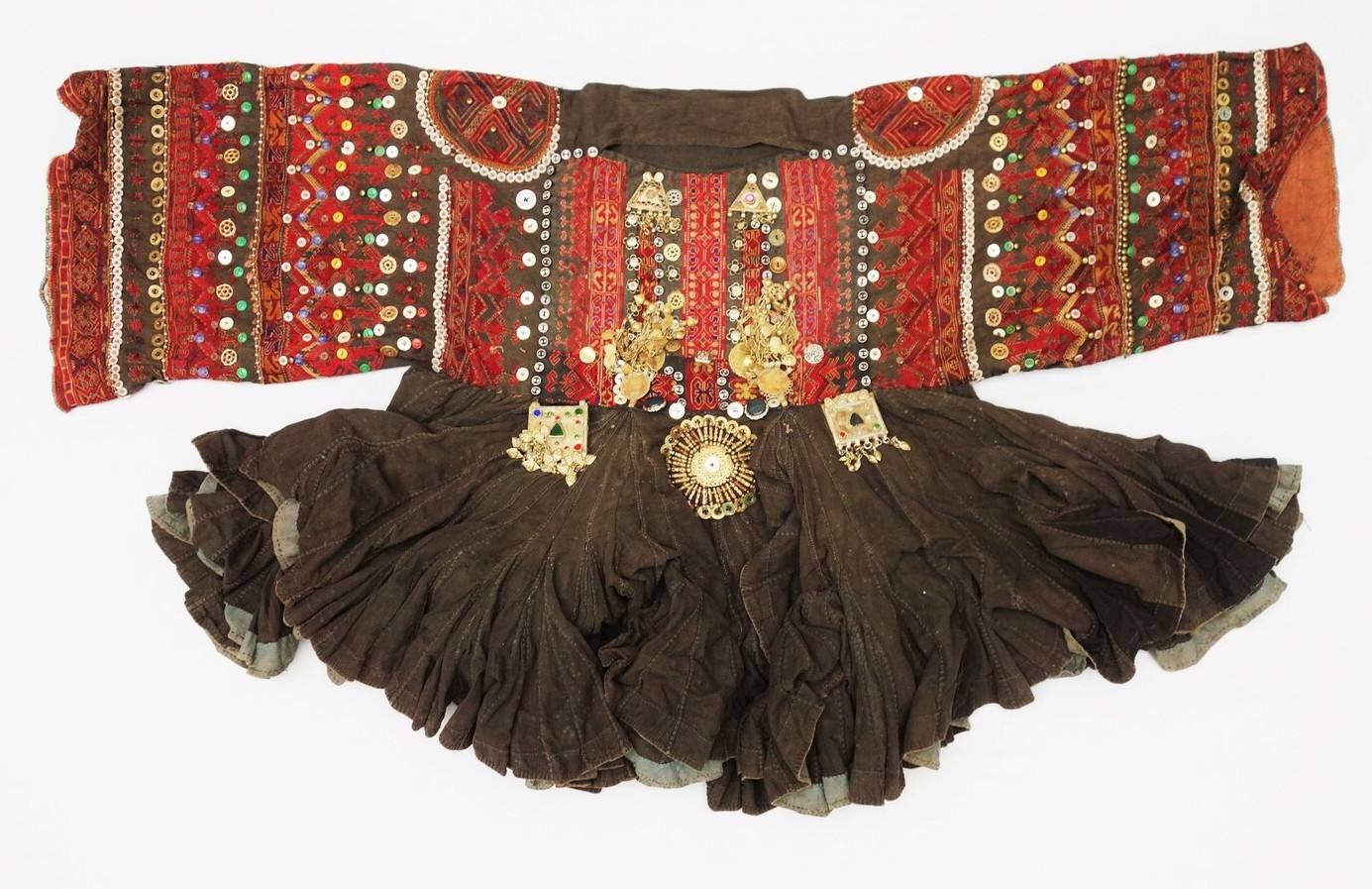 Woman's dress from Khyber Pakhtunkhwa, Pakistan, 20th century (TRC 1998.0032). The dress is made from black cotton and heavily decorated with embroidery on the sleeves. The embroidery is in red, yellow and orange yarns. There are also numerous applied buttons, beads, amulets, chains, coins, etc. The skirt is made up of over 700 panels.