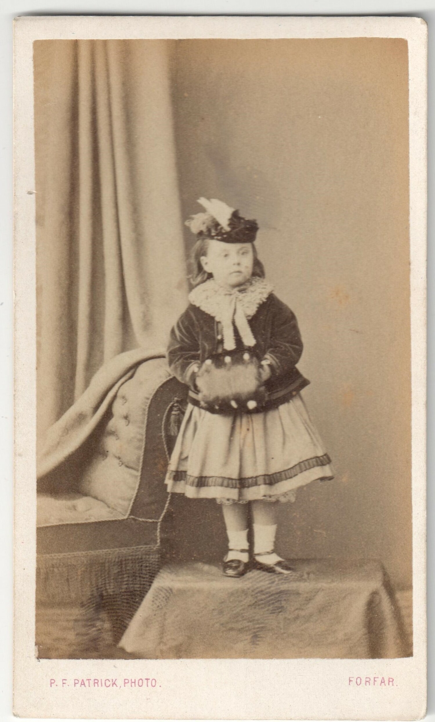 Late 19th century photograph showing a young girl from Scotland with her hands tucked into a muff (TRC 2019.0002).