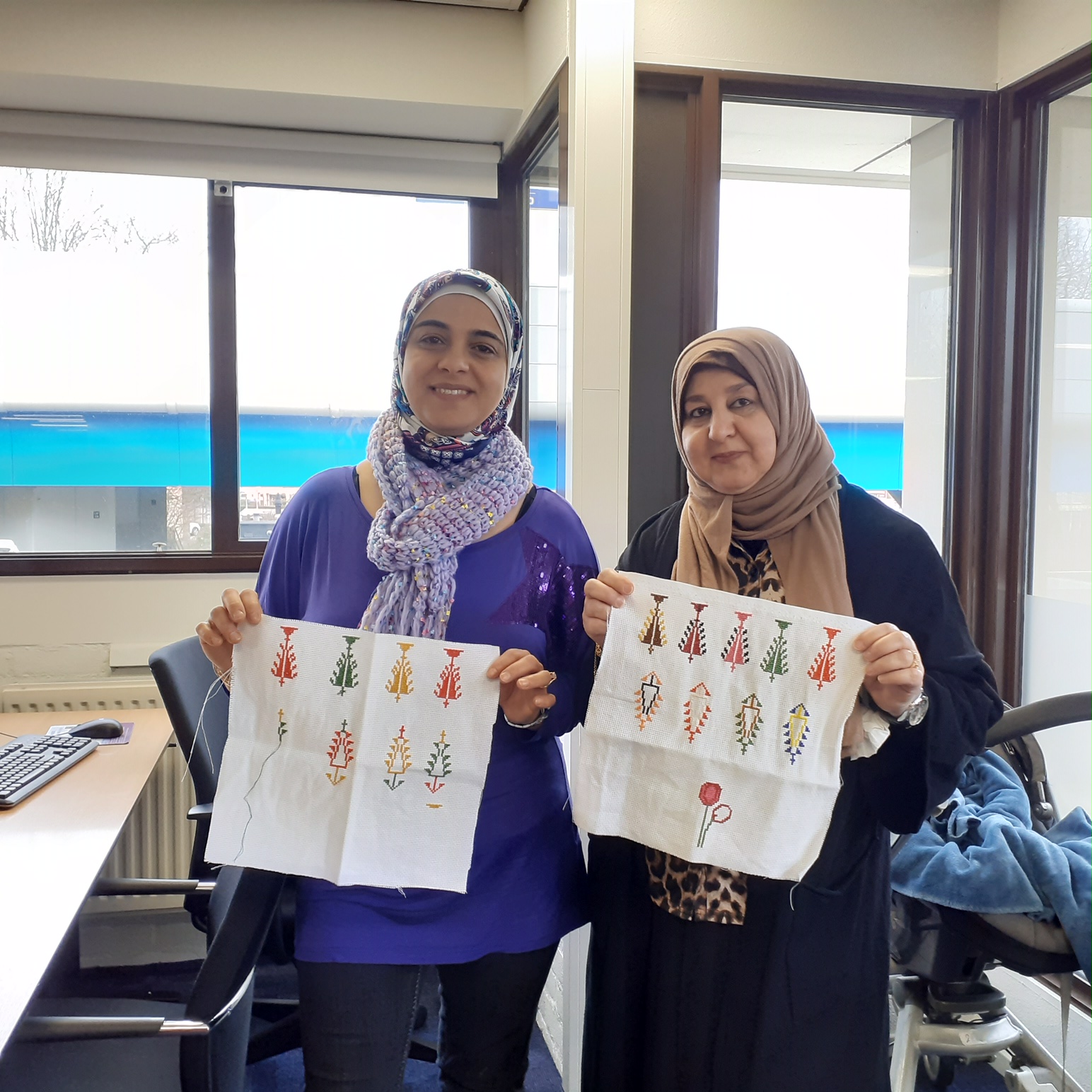 Two Middle Eastern women in Capelle a/d IJssel, proudly showing their embroidery.