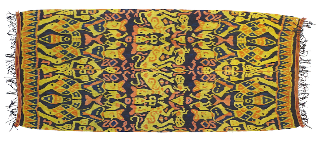 Ikat cloth from East Sumba, Indonesia, 1950-1975, with a repeating design of large stylised human figures, birds (especially peacocks), snakes and animals in yellow and red on a dark blue ground (TRC 2022.0905).