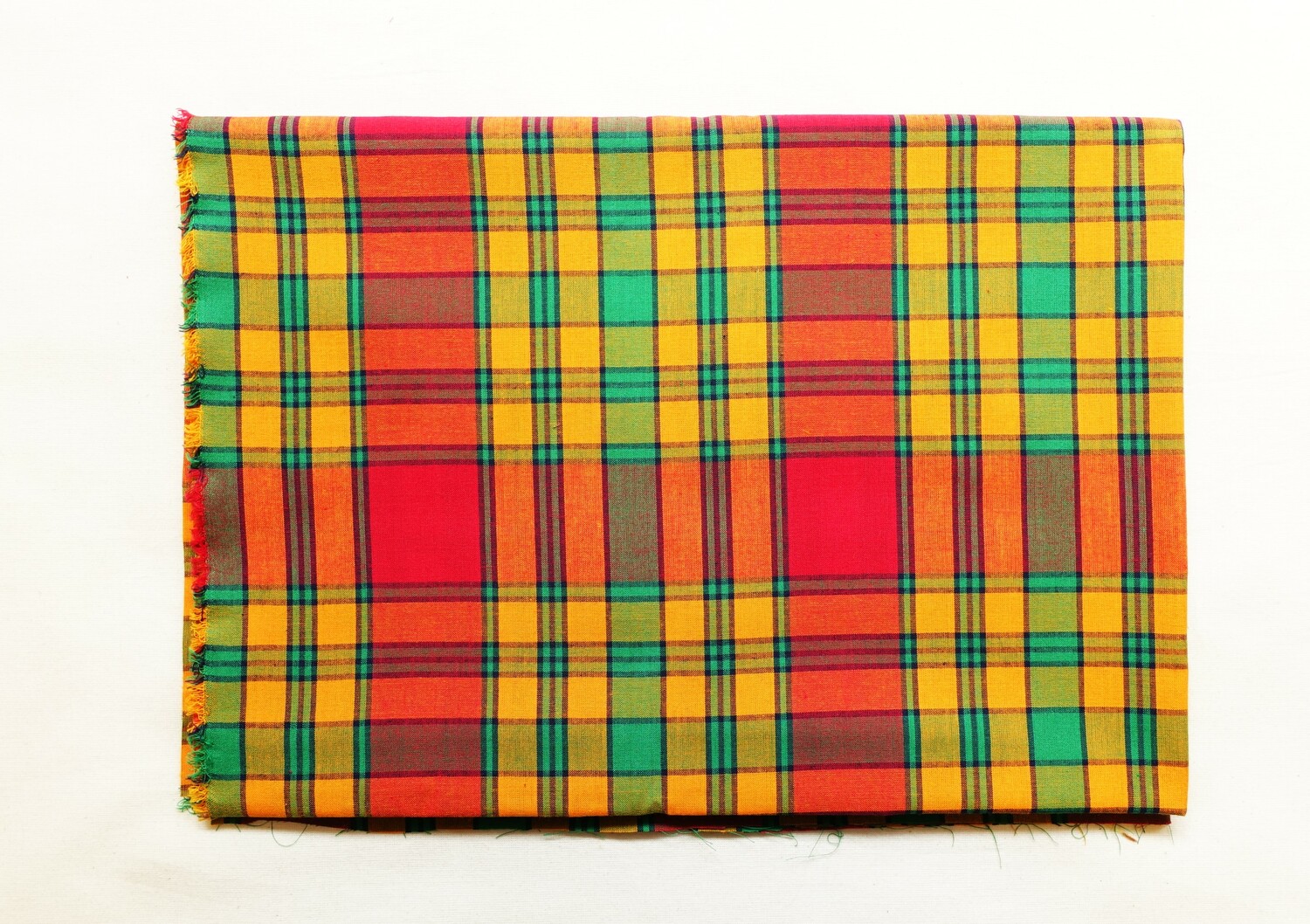 Length of Madras/George cloth with a checked/tartan design in orange, red, green and black (TRC 2022.2393). Madras or George cloth originates from Madras and the British fortress of St George, and became popular in western Africa (and Surinam in South America).