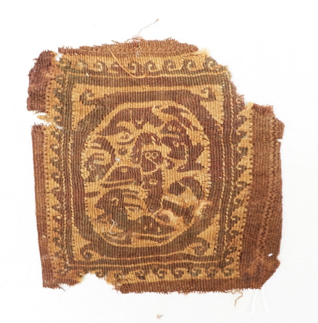 Fig. 1. Egyptian woven fragment from the 1st millennium AD, with stylised figures and waves, all in dark purple on an unbleached linen ground (TRC 2023.0073).