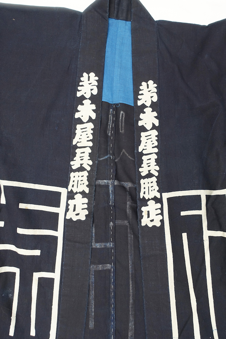 Front of jacket made from a dark blue cotton cloth with white, resist dyed motifs and texts in Japanese. Japan, 20th century (TRC 2024.1141).