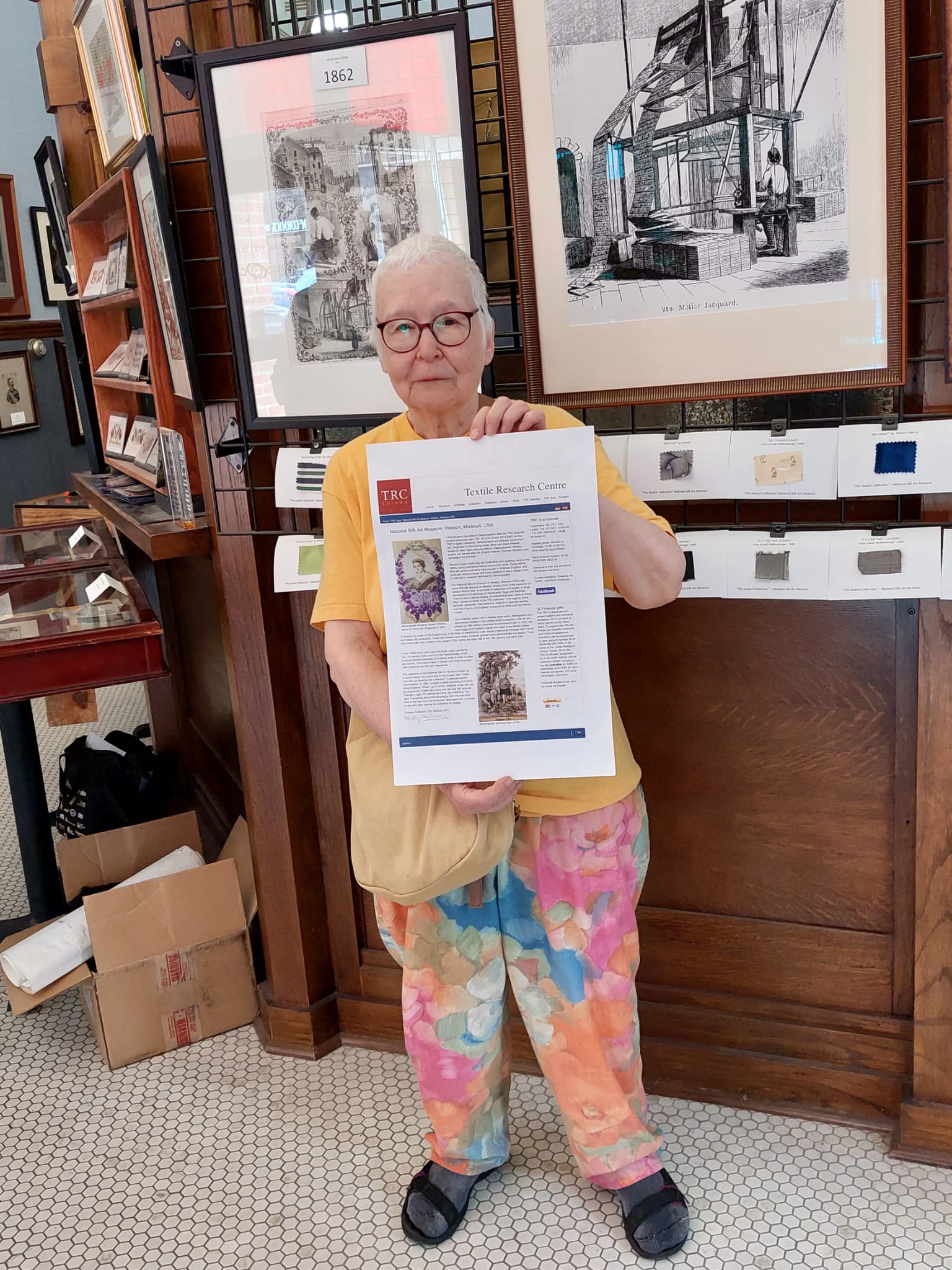 Photo: TRC volunteer Shelley Anderson holding a copy of the TRC blog inside the National Silk Museum, USA. Photo by Francoise Pottier.