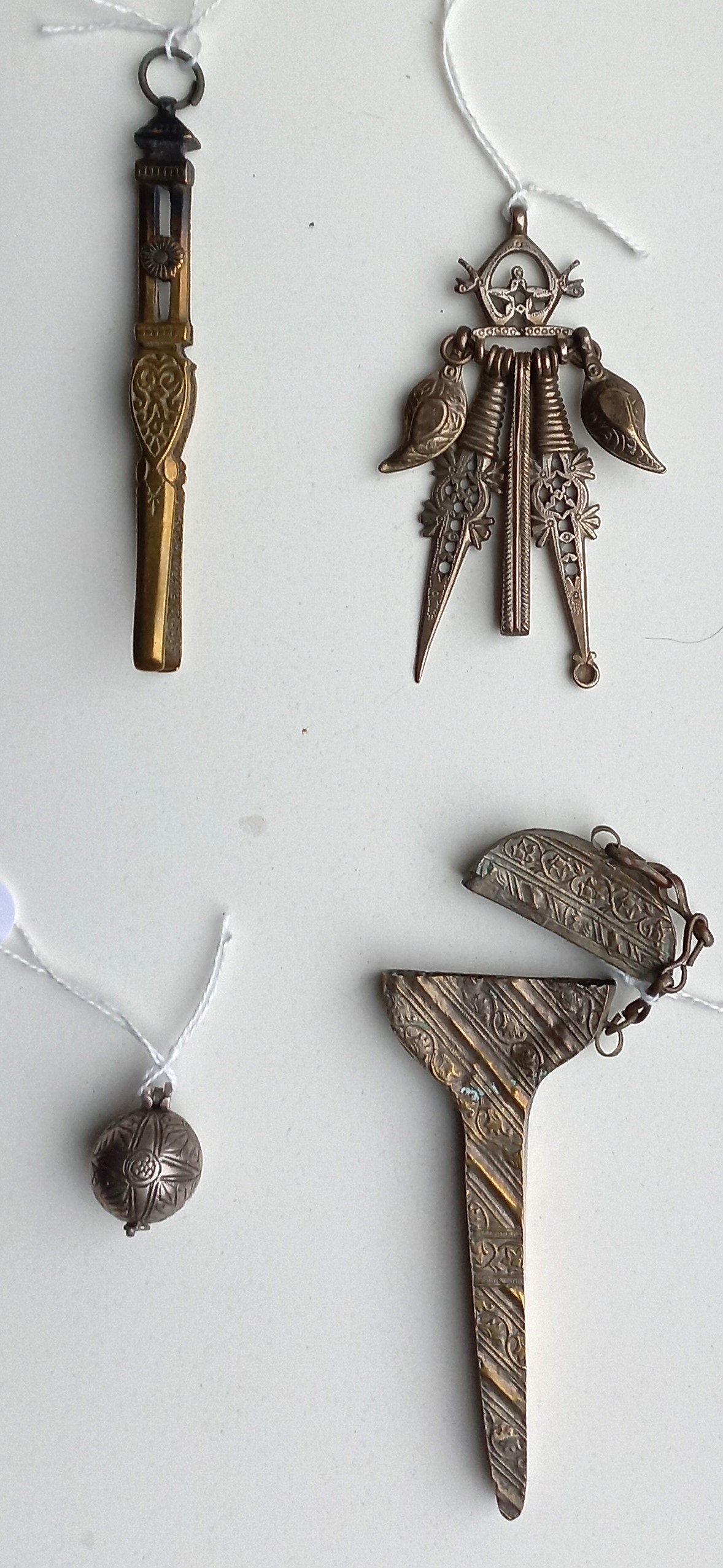 From left to right and top to bottom: Pair of ornate tweezers, a toilette set with tweezers and scoops, an ink ball, and a scissor case. Afghanistan, 1960s-1970s.